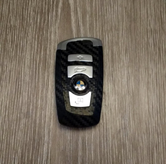 SuperWrappz LATCH key wrap in carbon, fitted to a BMW F-series blade key fob. Aftermarket vinyl — not genuine BMW parts.