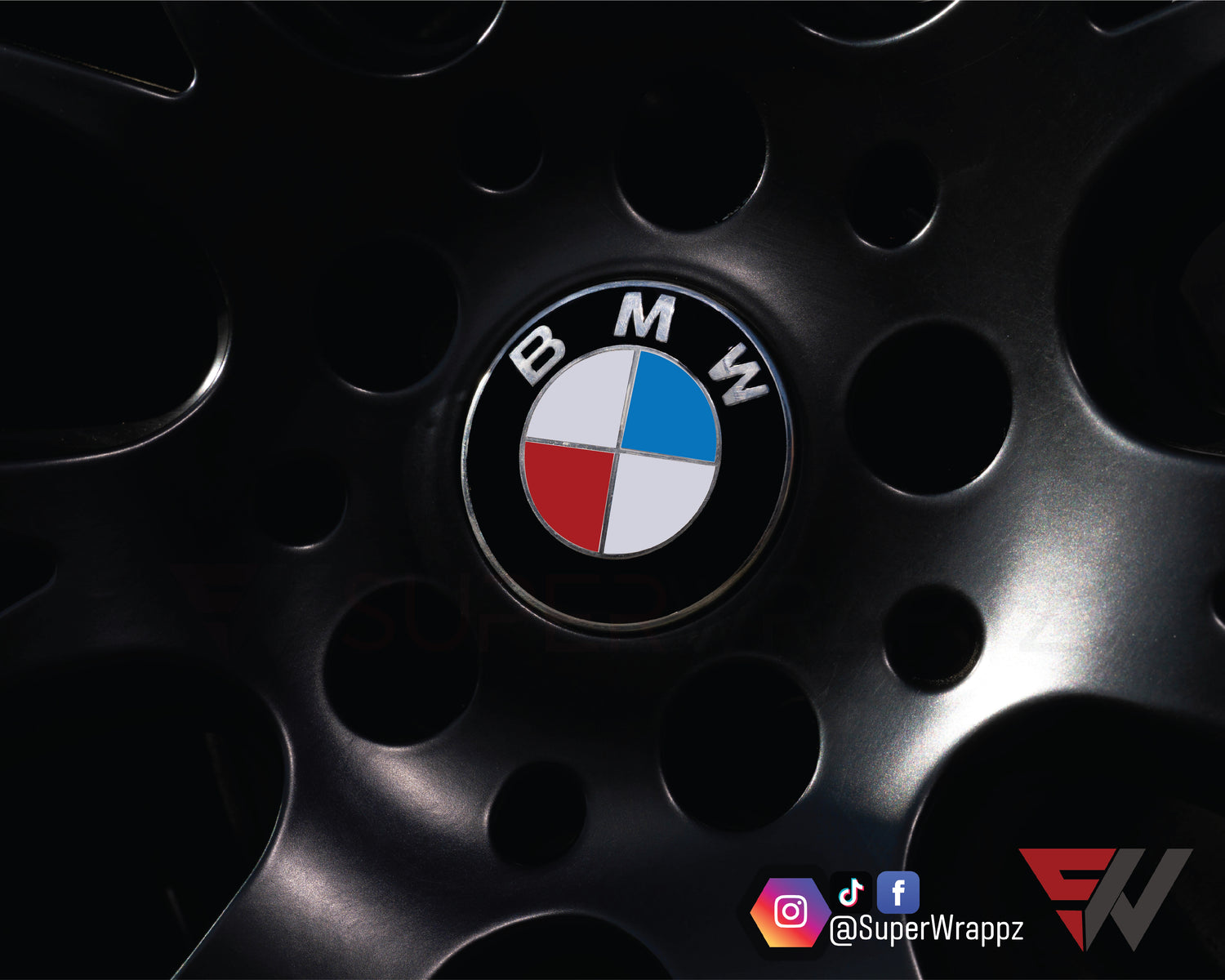 UK, USA & France Flag BMW badge overlay on an alloy wheel centre cap, close-up