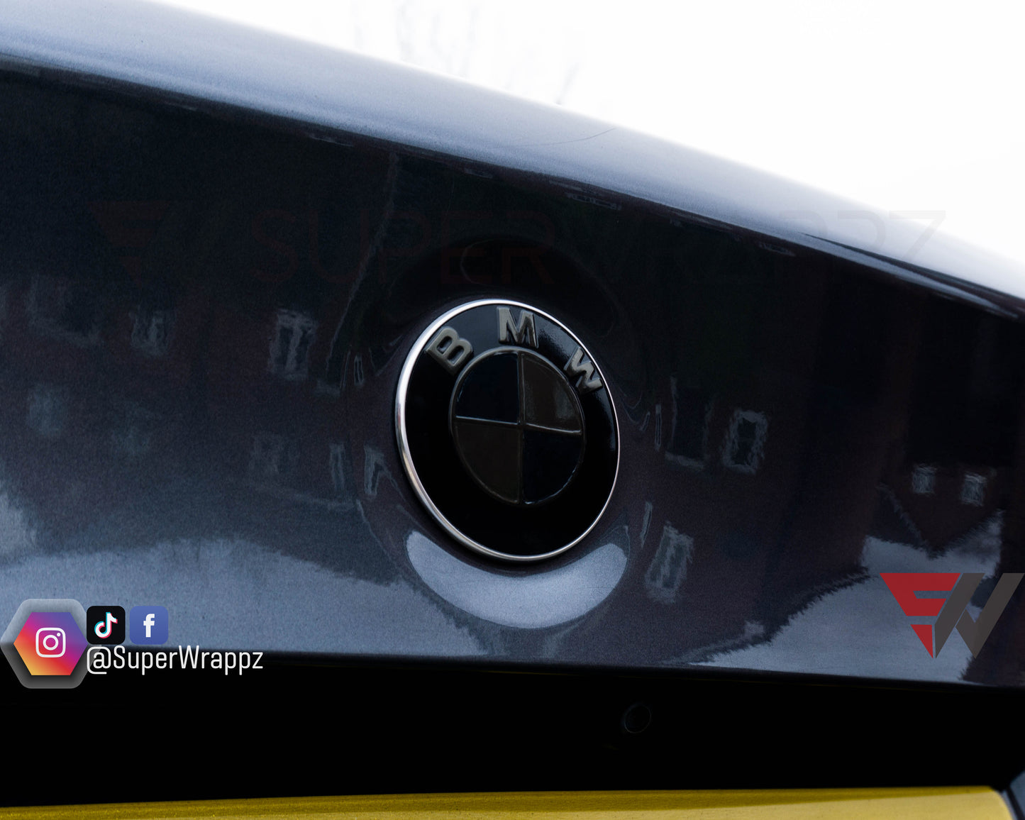 Dark Smoke 9-Piece BMW badge tint overlay on the front hood badge, close-up