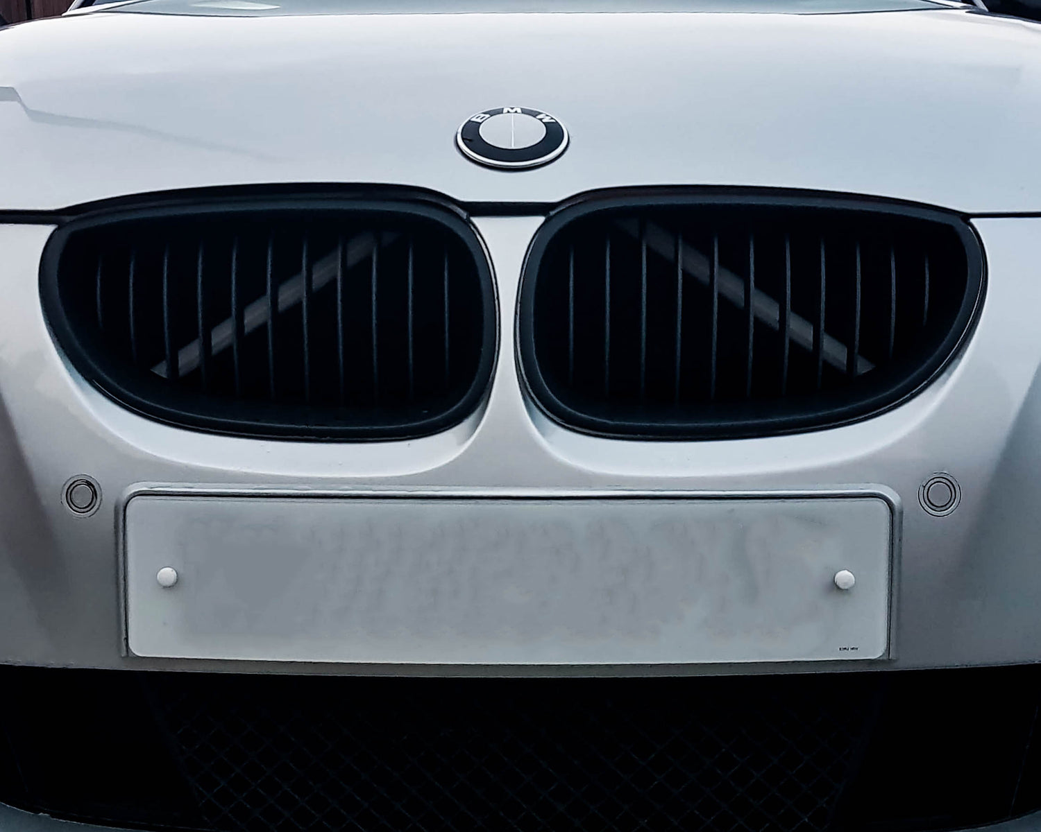 Close-up of a BMW front grille with the white reflective V-brace installed