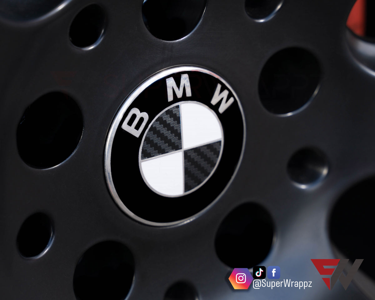 Half Black Carbon BMW badge overlay applied to an alloy wheel centre cap, close-up