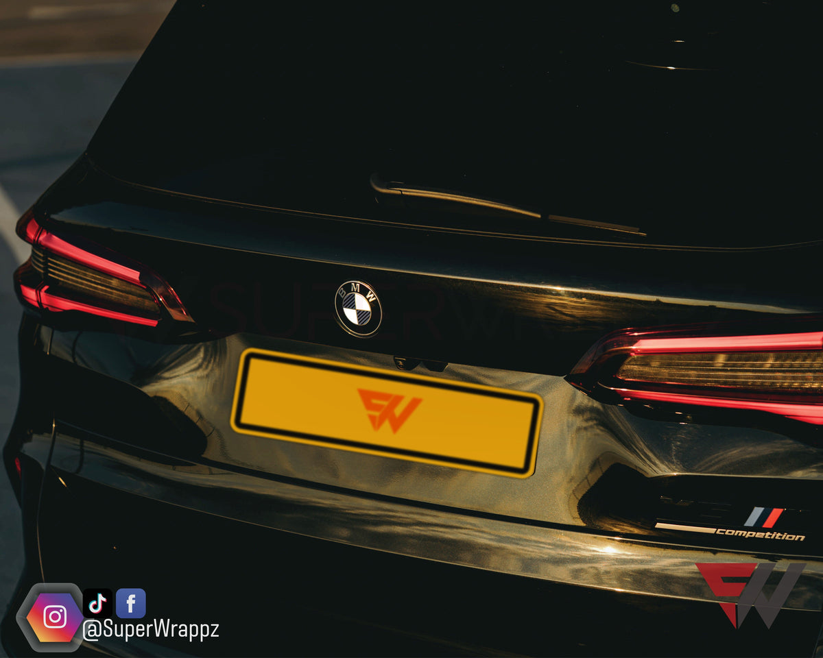 Half Black Carbon V2 BMW badge overlay on the rear boot badge, close-up