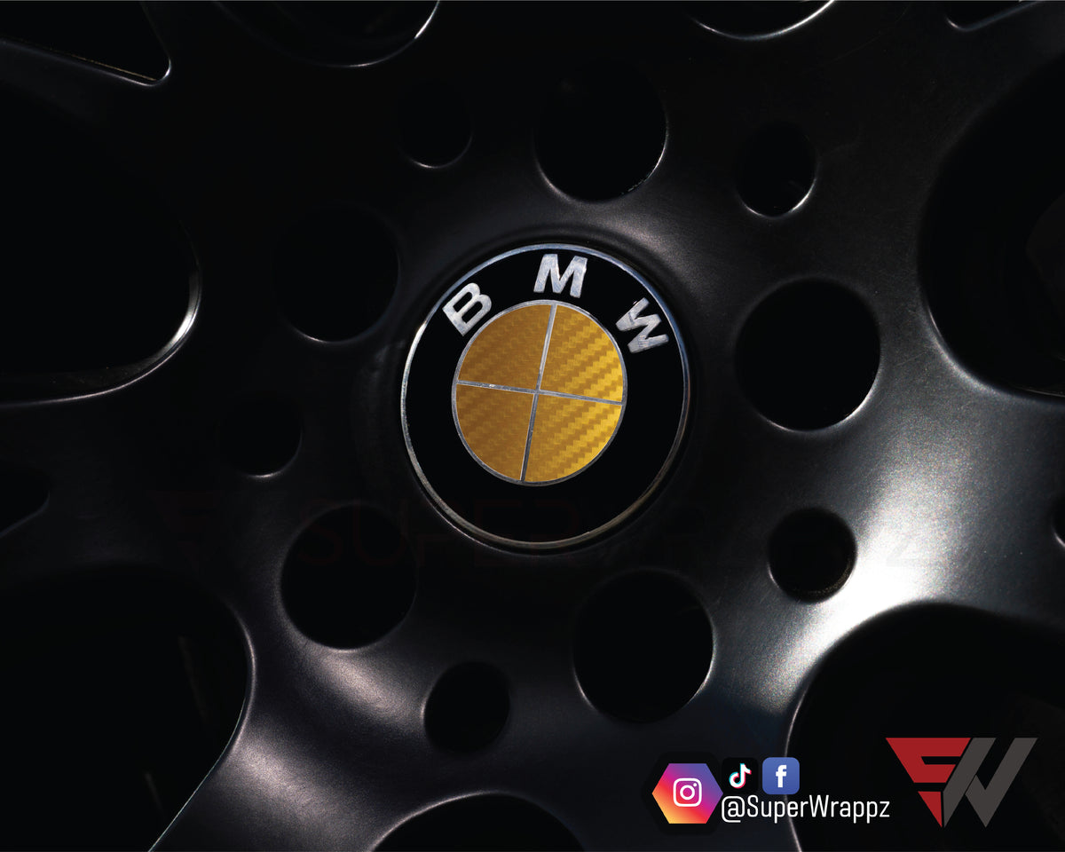 Full Gold Carbon BMW badge overlay applied to an alloy wheel centre cap, close-up