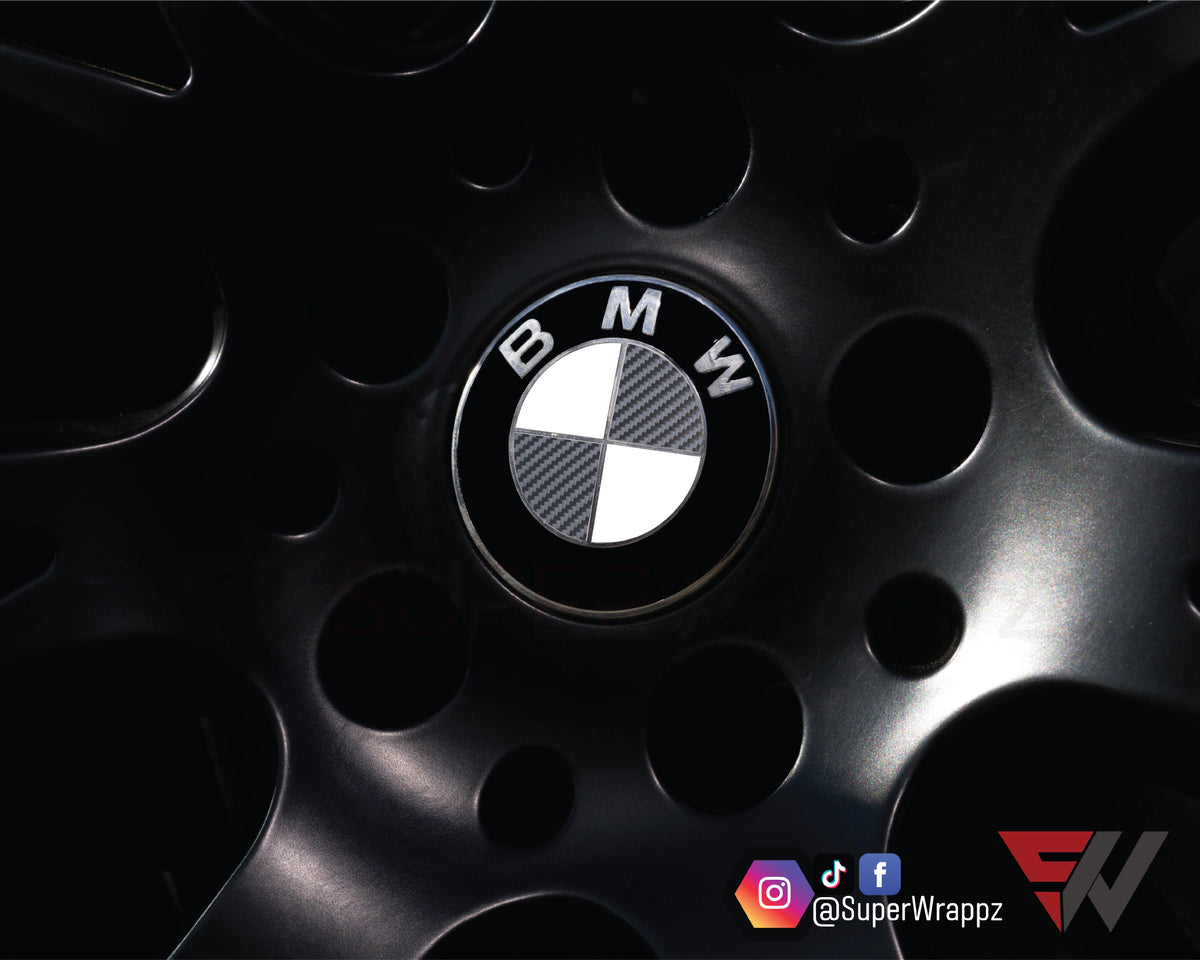 Half Dark Grey Carbon BMW badge overlay on an alloy wheel centre cap, close-up
