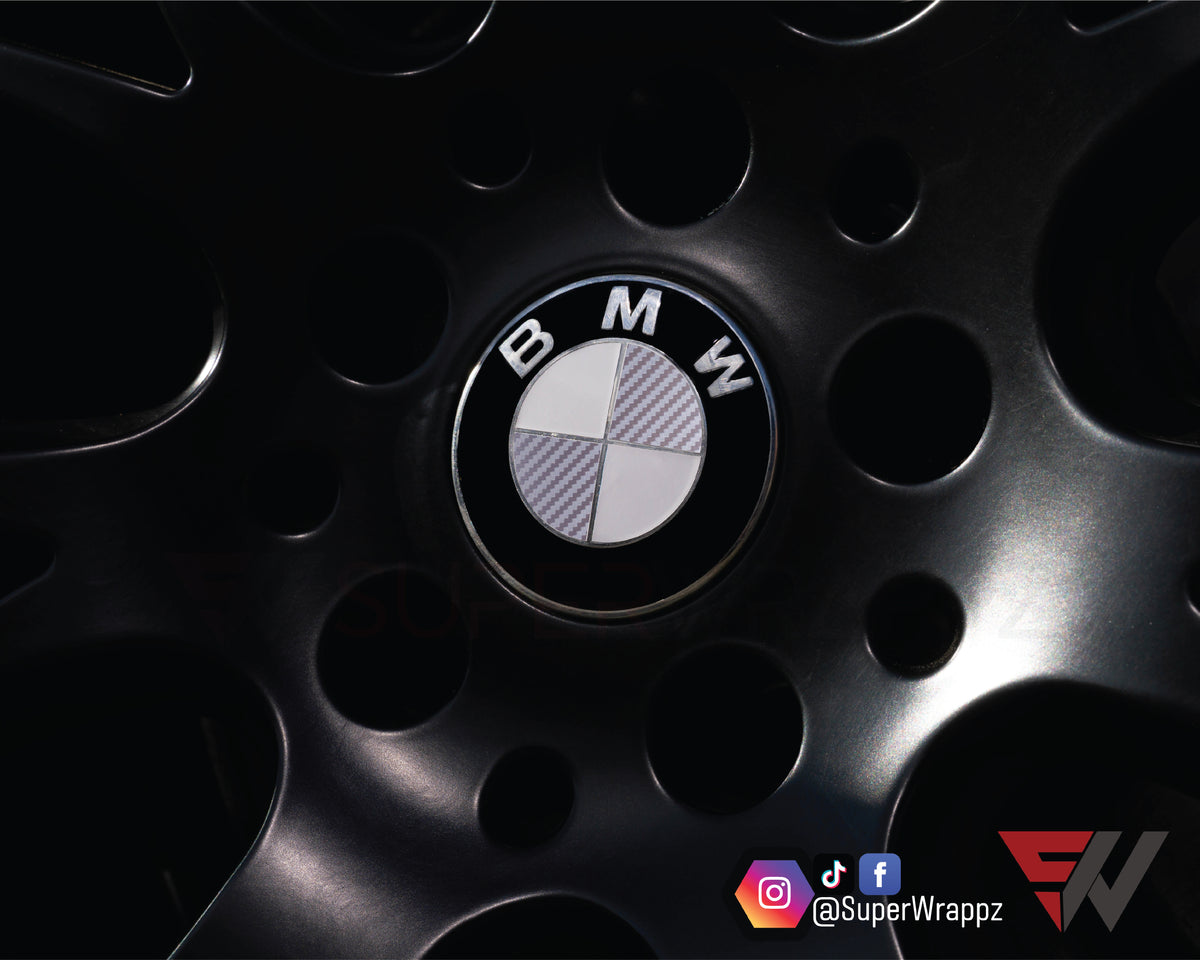 Half Silver Carbon BMW badge overlay on an alloy wheel centre cap, close-up