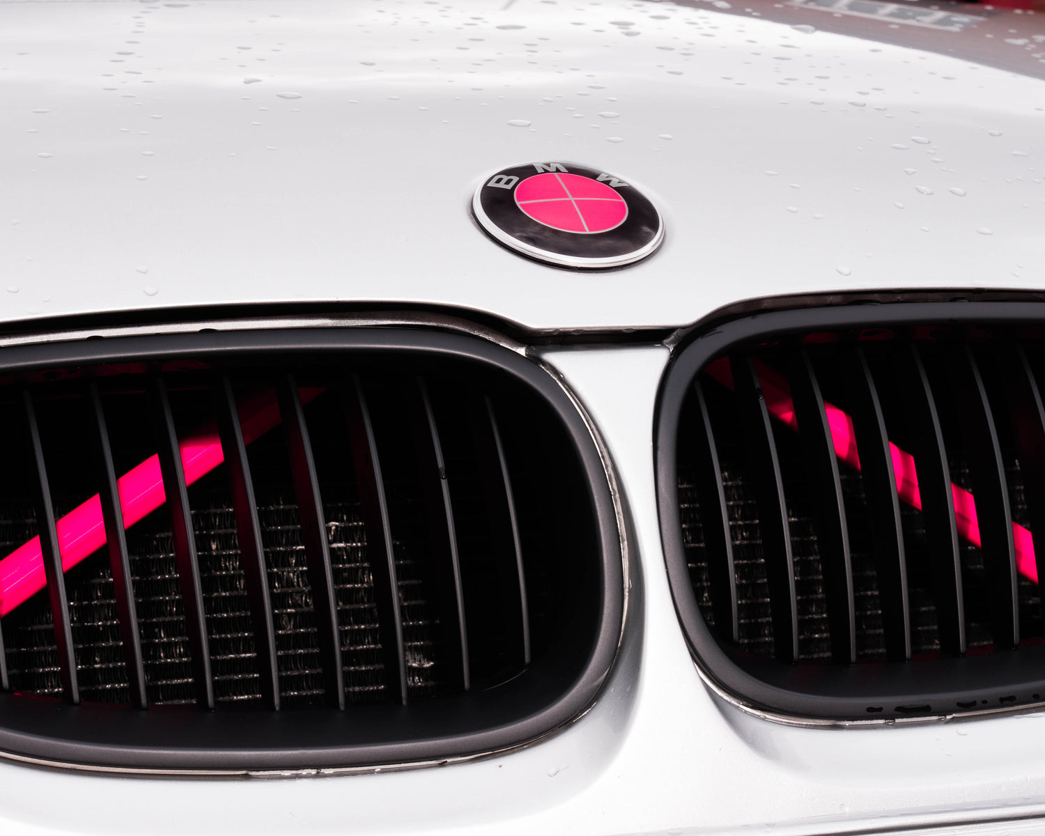 Close-up of a BMW front grille with the pink reflective V-brace installed