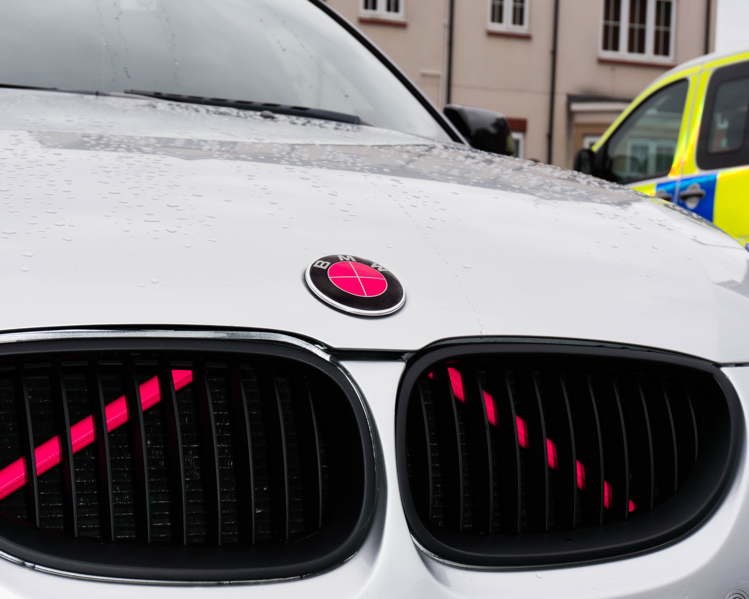 Close-up of a BMW front grille with the pink reflective V-brace installed