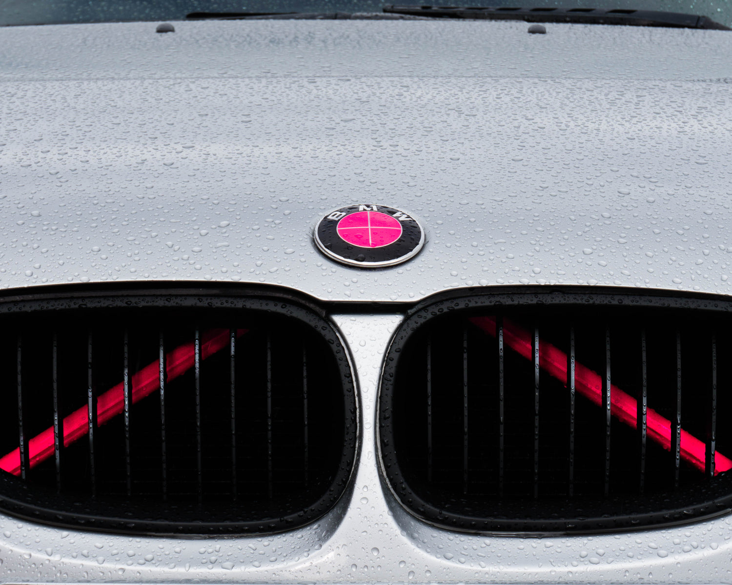 Close-up of a BMW front grille with the pink reflective V-brace installed