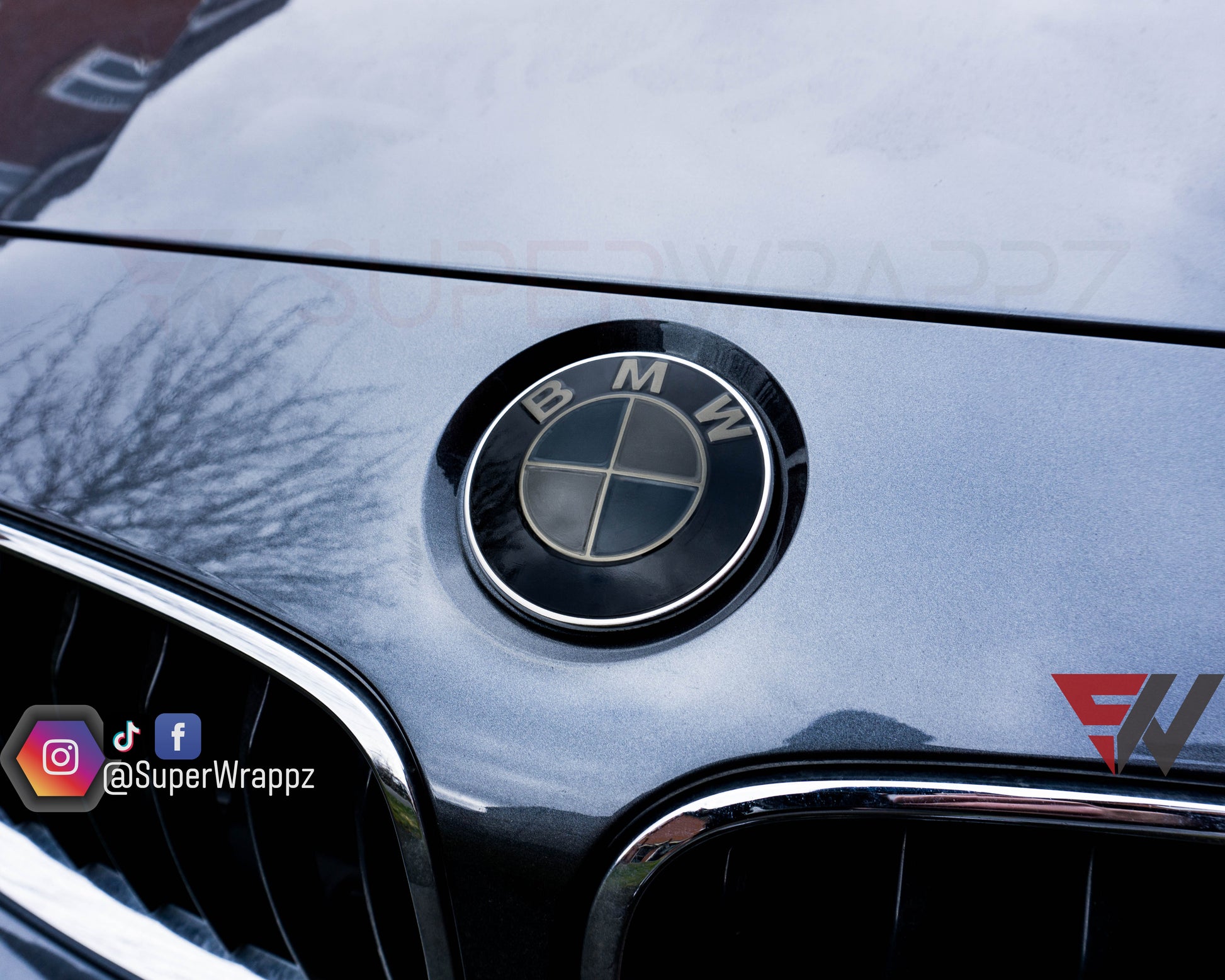 Dark smoke 9-piece BMW badge tint overlay by SuperWrappz on E/F Series emblems, aftermarket vinyl
