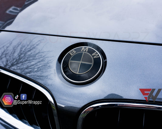 Dark smoke 9-piece BMW badge tint overlay by SuperWrappz on E/F Series emblems, aftermarket vinyl