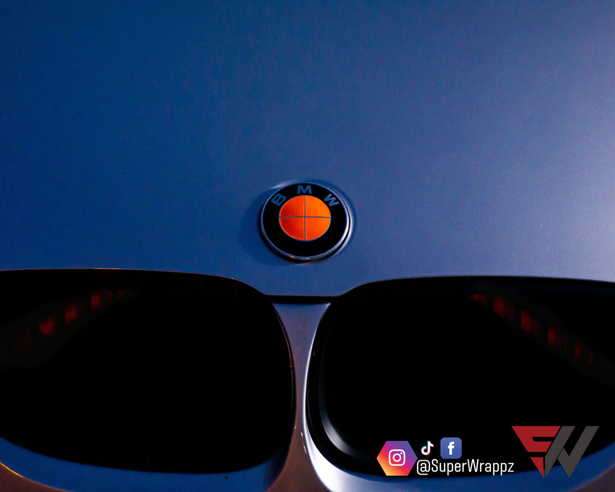 Full Orange Fluorescent BMW badge overlay applied to the front hood badge, close-up