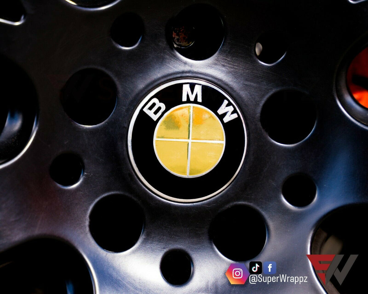Chrome Gold BMW badge overlay applied to an alloy wheel centre cap, close-up